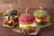 Three burgers with different bread buns red, green, black on wood background