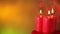 Three burning christmas candles spinning against warm colored blurry xmas background