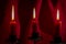 Three burning red candles against velvet drapes