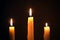 Three burning wax candles on a black background, religion, holidays