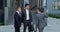 Three businessmen shake hands and talk together. Modern office building on the background. Male business, career