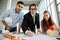 Three businesspeople team, female secretary, a boss in formal suit and male engineer standing together in modern office and