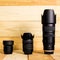 Three Camera Lenses with Lens Hoods Against a Wooden Background