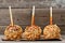 Three caramel apples with nuts against rustic wood