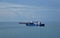 Three cargo ships are sailing through the cam, blue sea.