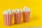 Three carton bucket with cinema snack. popcorn and red cups on color yellow background. space for text