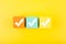 Three checkmarks on colorful blocks against bright yellow background