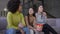 Three cheerful absorbed multiethnic women watching film movie on TV eating popcorn and talking in slow motion. Young