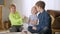 Three cheerful children fighting for tablet sitting in living room at home. Positive joyful Caucasian boys and girl