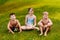 Three cheerful happy children in bathing suits sit on the green grass and look at the camera