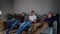 Three cheerful young guys use phones on a soft couch.