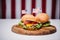 Three cheeseburgers with little american flags on wooden board, us flag on background