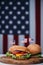 Three cheeseburgers with little american flags on wooden board, us flag on background