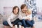 Three children, boy brothers, reading book at home at night on Christmas evening