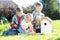 Three children boys - two teenagers and one preschooler making together nesting box sitting on lawn in summerday