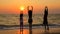 Three Children Doing Yoga Exercises On The Beach