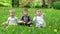 Three children on the grass on which the petals are falling from the trees, slow motion