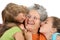 Three children kiss their grandmother on white background