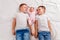 Three children lie on their backs on white sheet. Two older brothers and a newborn baby girl