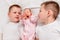 Three children lie on their backs on white sheet. Two older brothers and a newborn baby girl