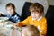 Three children, siblings eating vegetable soup at home. Two school kid boys and baby girl in domestic kitchen. Children