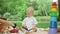 Three children sitting on blanket in park. Siblings spending time outdoors