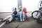 Three children skated on a skateboard and a bicycle and sat down to rest on the curb.