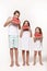 Three children in the studio stand on a white background and eat pieces of watermelon.