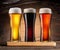 Three chilled glasses of different beer on wooden table closeup