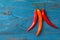 Three chilli peppers on blue wooden background