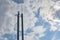 Three chimneys boiler room with antenna on top against a blue sky with clouds.