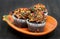 Three chocolate fall decorated cupcakes on a pumpkin plate.