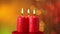 Three christmas candles burning on blurry xmas lights background