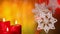Three christmas candles and xmas decorations hanging against blurry lights background