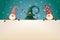 Three Christmas Gnomes with signboard on turquoise background. One hidden in Christmas tree