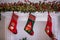 Three Christmas socks decorated with owl figures hanging on a shelf under advent garland