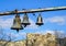 Three church bells of small, medium and large size hanging in chains against a blue sky whit white clouds