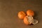 Three clementines on brown paper, one half-peeled