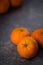 Three clementines on a dark stone countertop