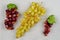 Three clusters of red and white grapes on a light brown background