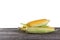 Three cobs of corn with green leaves on wooden table