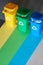 Three color coded recycle bins, isometric picture on geometric layered paper background. Recycling sign on blue, yellow and green