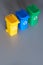 Three color coded recycle bins, isometric picture on geometric paper background with copy-space. Recycling sign on the bins, blue