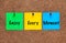 Three colored notes on a corkboard with words Enjoy Every Moment