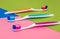 three colored toothbrushes - orange, blue and pink, lying on a colored paper background