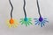 Three colorful lamps of blue, violet and orange colors hang on even wires against a gray wall.