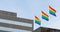 Three colorful rainbow flags, a symbol of LGBT, gay pride symbol on the light sky background.