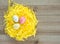 Three colorful speckled Easter eggs in yellow Easter grass on a wooden background