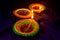 Three colorful terracotta oil lamp or diya lit during diwali on blue cloth background