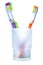 Three colorful toothbrushes in glass, two against one